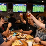 Patrons celebrating and placing bets on the GG88 platform in a lively sports bar environment.
